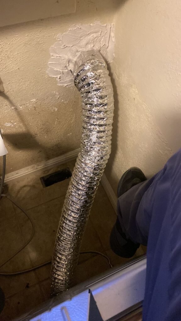 A professional dryer vent cleaning service technician inspecting a dryer vent for lint buildup and blockages in a residential home in May 2025.